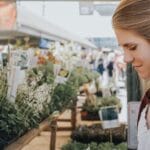 A young woman browses plants at a garden centre.